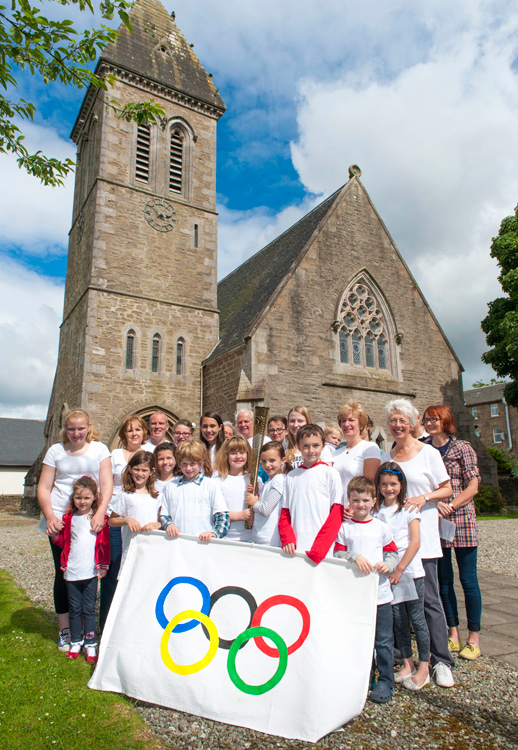 Some of the children and adult helpers with the olympic torch and flag.